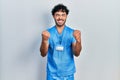 Young hispanic man wearing blue male nurse uniform excited for success with arms raised and eyes closed celebrating victory Royalty Free Stock Photo