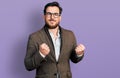 Young hispanic man wearing business jacket and glasses excited for success with arms raised and eyes closed celebrating victory Royalty Free Stock Photo