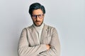 Young hispanic man wearing business jacket and glasses skeptic and nervous, disapproving expression on face with crossed arms Royalty Free Stock Photo