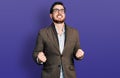 Young hispanic man wearing business jacket and glasses very happy and excited doing winner gesture with arms raised, smiling and Royalty Free Stock Photo
