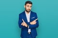 Young hispanic man wearing business jacket pointing to both sides with fingers, different direction disagree