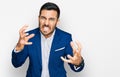 Young hispanic man wearing business jacket shouting frustrated with rage, hands trying to strangle, yelling mad Royalty Free Stock Photo