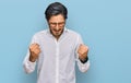 Young hispanic man wearing business shirt and glasses excited for success with arms raised and eyes closed celebrating victory Royalty Free Stock Photo