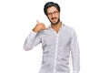 Young hispanic man wearing business shirt and glasses smiling doing phone gesture with hand and fingers like talking on the Royalty Free Stock Photo