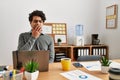 Young hispanic man wearing business style sitting on desk at office bored yawning tired covering mouth with hand Royalty Free Stock Photo