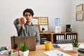 Young hispanic man wearing business style sitting on desk at office looking unhappy and angry showing rejection and negative with Royalty Free Stock Photo