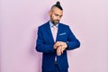 Young hispanic man wearing business suit and tie checking the time on wrist watch, relaxed and confident Royalty Free Stock Photo