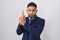 Young hispanic man wearing business suit and tie holding symbolic gun with hand gesture, playing killing shooting weapons, angry