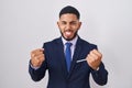 Young hispanic man wearing business suit and tie very happy and excited doing winner gesture with arms raised, smiling and Royalty Free Stock Photo