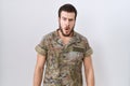 Young hispanic man wearing camouflage army uniform afraid and shocked with surprise expression, fear and excited face Royalty Free Stock Photo