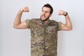 Young hispanic man wearing camouflage army uniform showing arms muscles smiling proud Royalty Free Stock Photo