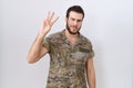 Young hispanic man wearing camouflage army uniform showing and pointing up with fingers number three while smiling confident and Royalty Free Stock Photo