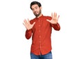 Young hispanic man wearing casual clothes afraid and terrified with fear expression stop gesture with hands, shouting in shock Royalty Free Stock Photo