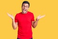 Young hispanic man wearing casual clothes and glasses celebrating victory with happy smile and winner expression with raised hands Royalty Free Stock Photo