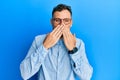 Young hispanic man wearing casual clothes and glasses laughing and embarrassed giggle covering mouth with hands, gossip and