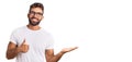 Young hispanic man wearing casual clothes and glasses showing palm hand and doing ok gesture with thumbs up, smiling happy and Royalty Free Stock Photo