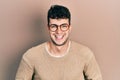 Young hispanic man wearing casual clothes and glasses smiling and laughing hard out loud because funny crazy joke with hands on Royalty Free Stock Photo