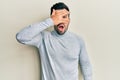 Young hispanic man wearing casual clothes peeking in shock covering face and eyes with hand, looking through fingers afraid Royalty Free Stock Photo