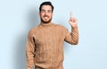 Young hispanic man wearing casual clothes showing and pointing up with finger number one while smiling confident and happy Royalty Free Stock Photo