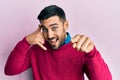 Young hispanic man wearing casual clothes smiling doing talking on the telephone gesture and pointing to you Royalty Free Stock Photo