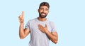 Young hispanic man wearing casual clothes smiling swearing with hand on chest and fingers up, making a loyalty promise oath Royalty Free Stock Photo
