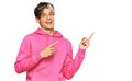 Young hispanic man wearing casual pink sweatshirt smiling and looking at the camera pointing with two hands and fingers to the Royalty Free Stock Photo