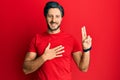 Young hispanic man wearing casual red t shirt smiling swearing with hand on chest and fingers up, making a loyalty promise oath Royalty Free Stock Photo