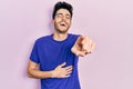Young hispanic man wearing casual t shirt laughing at you, pointing finger to the camera with hand over body, shame expression Royalty Free Stock Photo