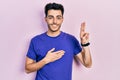 Young hispanic man wearing casual t shirt smiling swearing with hand on chest and fingers up, making a loyalty promise oath Royalty Free Stock Photo