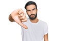 Young hispanic man wearing casual white t shirt looking unhappy and angry showing rejection and negative with thumbs down gesture Royalty Free Stock Photo