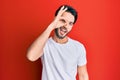 Young hispanic man wearing casual white tshirt doing ok gesture with hand smiling, eye looking through fingers with happy face Royalty Free Stock Photo
