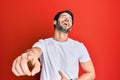 Young hispanic man wearing casual white tshirt laughing at you, pointing finger to the camera with hand over body, shame Royalty Free Stock Photo