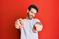 Young hispanic man wearing casual white tshirt pointing to you and the camera with fingers, smiling positive and cheerful Royalty Free Stock Photo