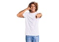 Young hispanic man wearing casual white tshirt smiling doing talking on the telephone gesture and pointing to you Royalty Free Stock Photo