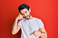 Young hispanic man wearing casual white tshirt smiling doing talking on the telephone gesture and pointing to you Royalty Free Stock Photo