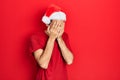 Young hispanic man wearing christmas hat with sad expression covering face with hands while crying Royalty Free Stock Photo