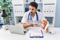 Young hispanic man wearing doctor uniform having teleconsultation at clinic Royalty Free Stock Photo