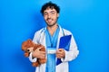 Young hispanic man wearing doctor uniform holding teddy bear and clipboard smiling with a happy and cool smile on face Royalty Free Stock Photo