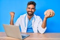 Young hispanic man wearing doctor uniform working at the clinic holding brain screaming proud, celebrating victory and success Royalty Free Stock Photo