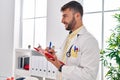 Young hispanic man wearing doctor uniform writing on clipboard at clinic Royalty Free Stock Photo