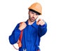 Young hispanic man wearing elecrician uniform holding cable pointing with finger to the camera and to you, confident gesture