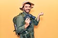 Young hispanic man wearing explorer clothes holding binoculars screaming proud, celebrating victory and success very excited with