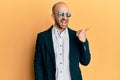 Young hispanic man wearing fashion sunglasses and business jacket pointing thumb up to the side smiling happy with open mouth Royalty Free Stock Photo