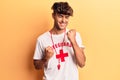 Young hispanic man wearing lifeguard t-shirt and whistle celebrating surprised and amazed for success with arms raised and eyes