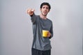 Young hispanic man wearing pajama drinking a cup of coffee pointing displeased and frustrated to the camera, angry and furious Royalty Free Stock Photo