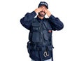 Young hispanic man wearing police uniform covering eyes with hands smiling cheerful and funny Royalty Free Stock Photo