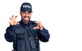 Young hispanic man wearing police uniform smiling funny doing claw gesture as cat, aggressive and sexy expression Royalty Free Stock Photo