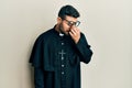 Young hispanic man wearing priest uniform standing over white background tired rubbing nose and eyes feeling fatigue and headache Royalty Free Stock Photo