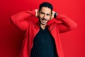 Young hispanic man wearing red leather jacket relaxing and stretching, arms and hands behind head and neck smiling happy Royalty Free Stock Photo