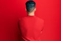 Young hispanic man wearing red leather jacket standing backwards looking away with crossed arms Royalty Free Stock Photo